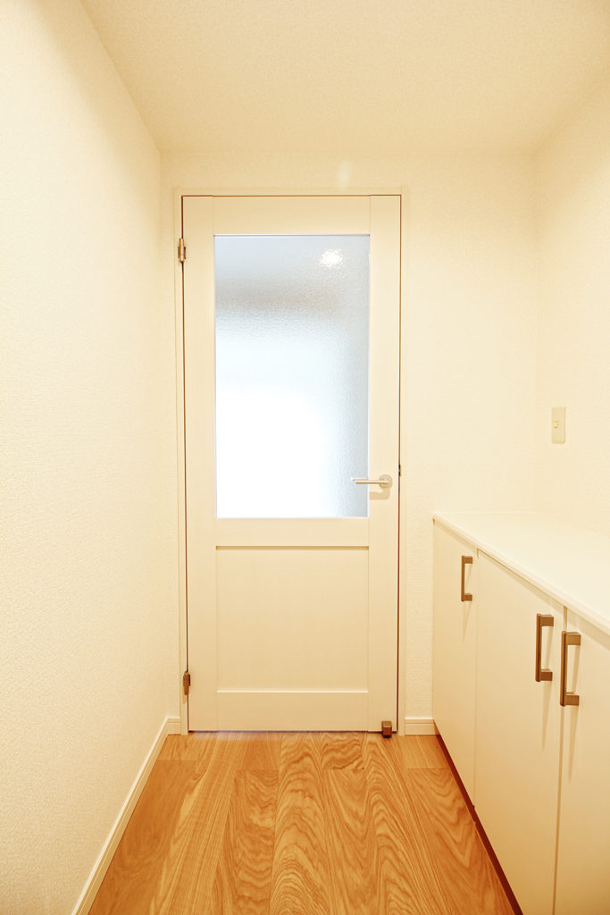 建具は、ウッドワン「ドレタス」のホワイト(メープル柄)を使用しています。玄関を開けるとリビングの光が廊下にさしこみます。