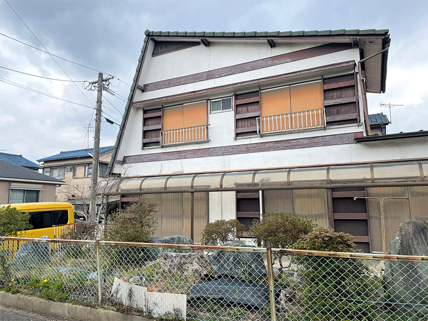 リノベーション前の住宅全景。大きな二階建ての外観と庭の植栽、古い面格子や雨よけが残る状態の記録写真