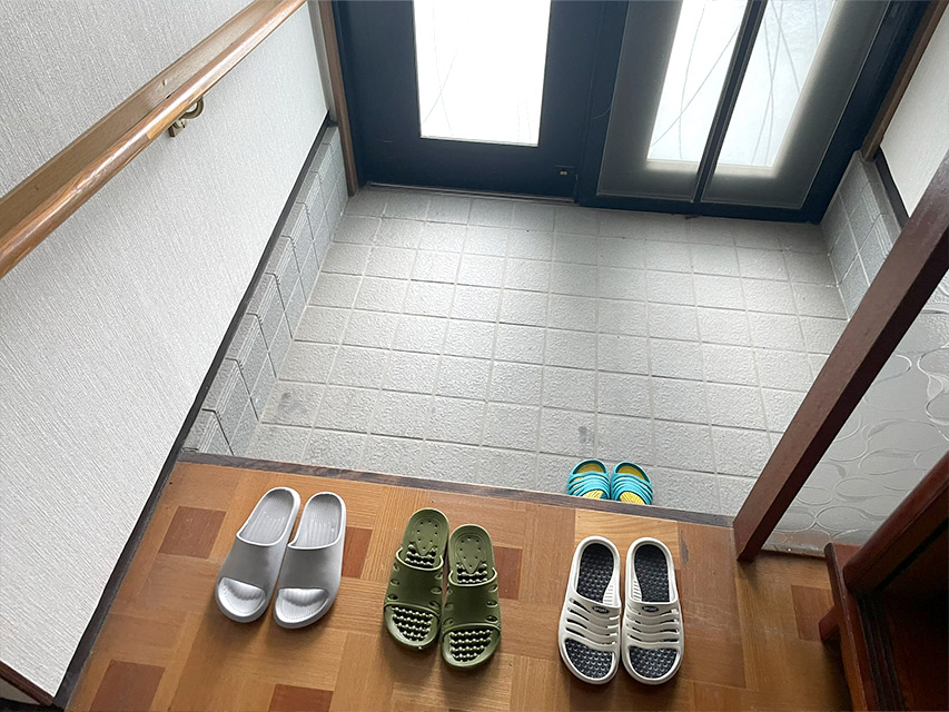 リノベーション前の玄関の様子。タイル張りの土間と並べられたスリッパがある状態を記録した写真