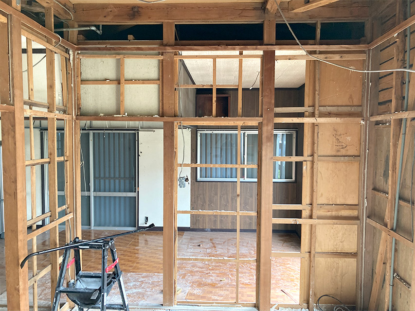 壁材を撤去して骨組みが露わになった室内の様子。柱や間柱が見え、隣室まで抜けて見える状態を記録した写真