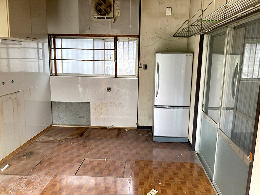 キッチンの設備を撤去した後の室内の様子。床や壁に使用感が残り、冷蔵庫だけが置かれている状態を記録した写真