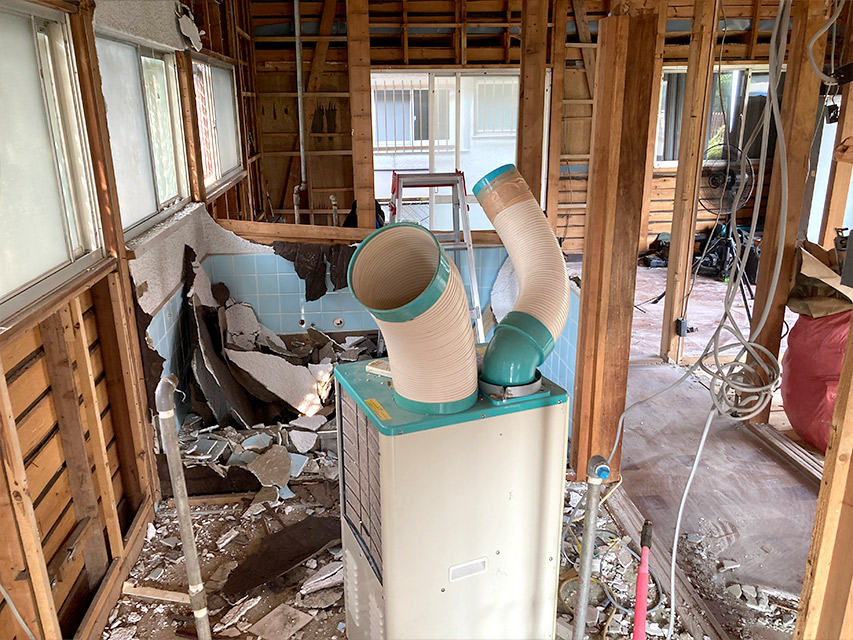 浴室まわりの壁材を解体し、タイル下地と配管が露わになった室内の写真