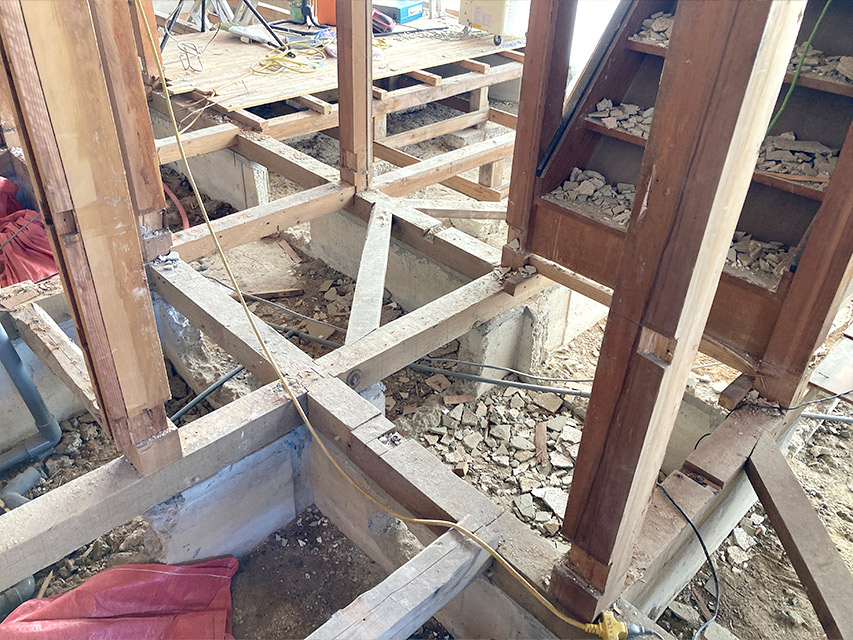 住宅の床を解体し、基礎部分と土台の木材が露出した状態を映した写真。