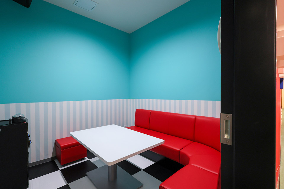 アメリカンダイナーのレトロポップな空間をビビットな水色と真っ赤なソファで再現。