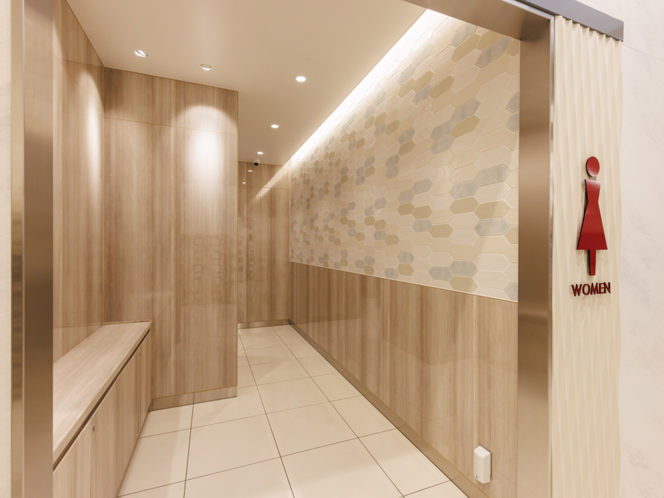 トイレの壁面は不燃化粧板をほぼ全面貼り、床もタイル貼で清潔感と意匠性に配慮しています。壁面アクセントのタイルは、柔らかいトーンの色調でデザイン貼りしています。長六角形の変形タイルでしたが、協力業者様の高い技術でとても美しい仕上がりにしていただきました。