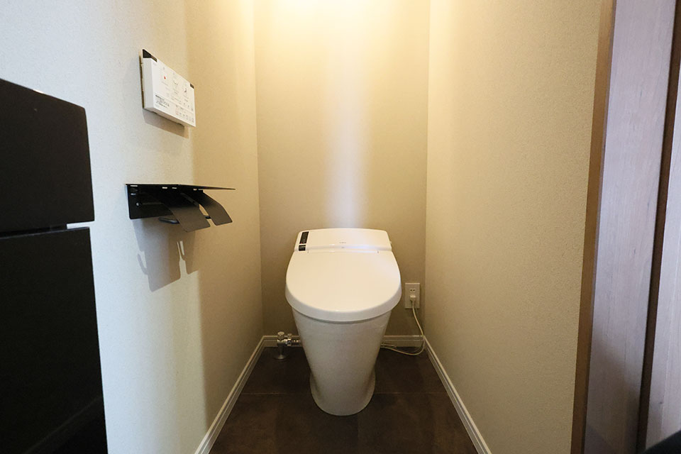 トイレはLIXIL製のタンクレストイレを採用し、手洗い器にはミラタップを選定しました。床は落ち着きのある色合いでまとめることで、空間全体を引き締めています。紙巻器や手洗い器のパーツにはブラックを取り入れ、シンプルながらも洗練された印象に仕上げました。